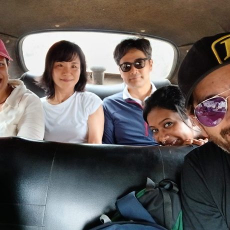 h2-pre_trip_info_local_female-guide_taking_a_group_selfie_with_tourists_inside_a_classic_kolkata-yellow_taxi