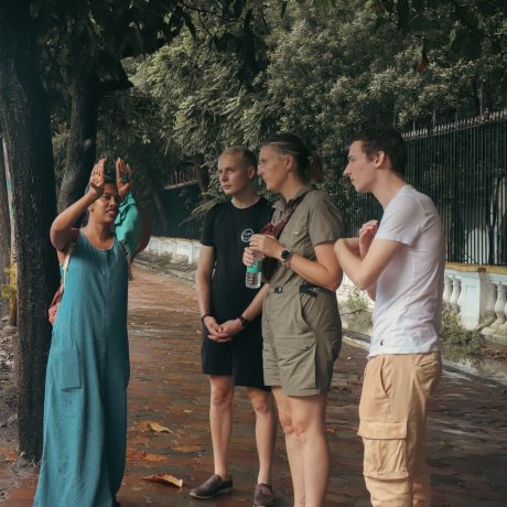 h2_fAQs_local_female-guide_speaking_to_tourists_on_a_tree_lined_street)_during_a_britisht_colonial_heritage_walk-in_kolkata